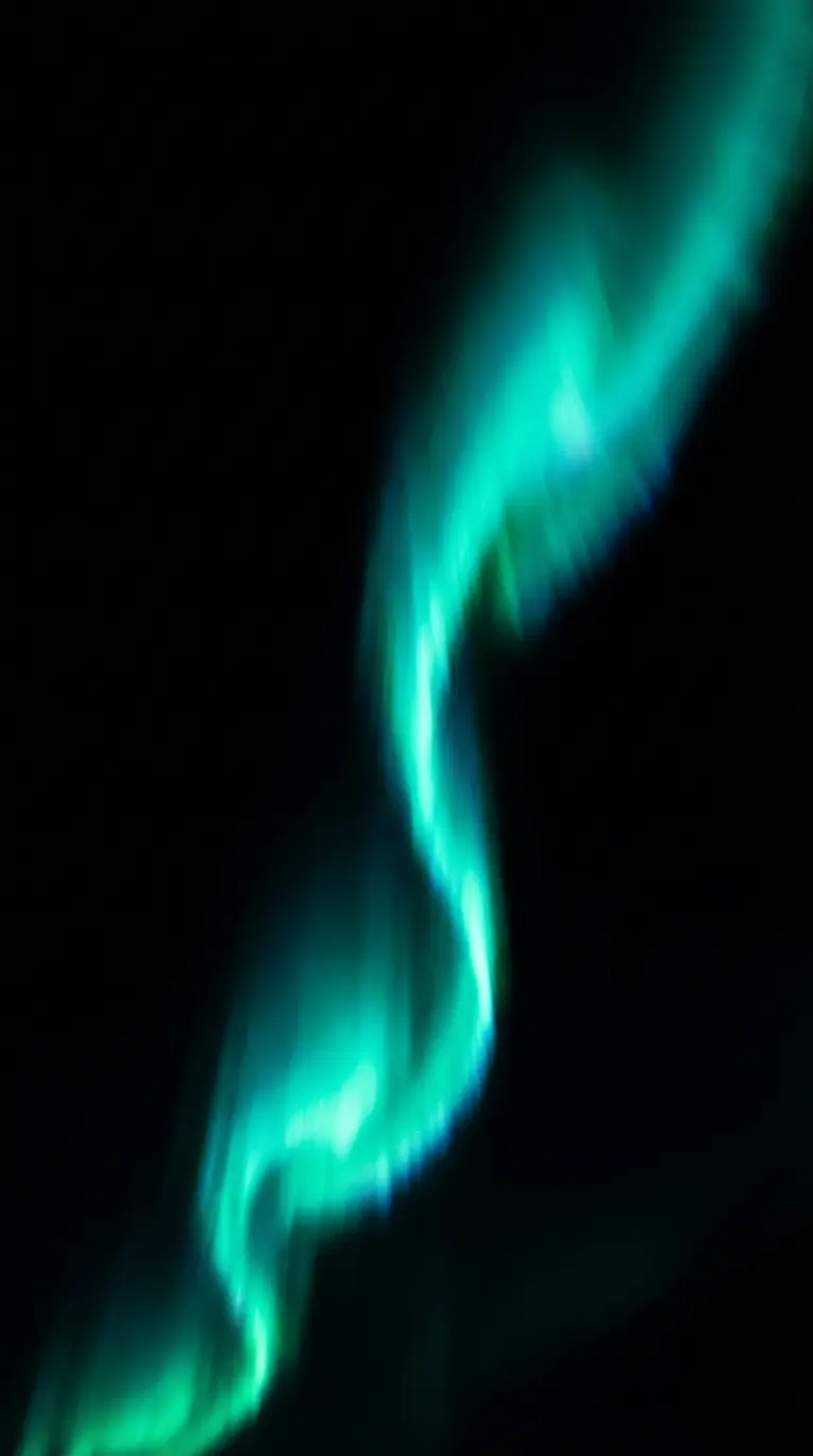 Teal Northern Lights aurora borealis streak against a pitch-black background
